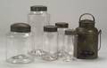 Five Covered Colorless Glass Cannisters and a Tin Lunch Carrier