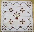 Appliqued quilt with red and green floral border and basket of flowers as center design