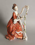Painted porcelain figure of a woman playing the harp