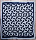 Blue and white pieced quilt in the Drunkards Path pattern