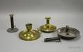 Two Brass Chambersticks an Iron Hogscraper Candlestick and a Tin Chamberstick