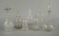 Seven colorless glass bottles and decanters
