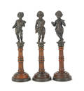 Three bronze figures of children on wooden columns