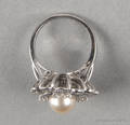 14K white gold diamond and pearl ring with a round setting containing an 8mm pearl surrounded by ribbons of single cut diamond accents