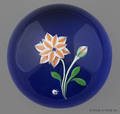 Baccarat paperweight with an orange and white flower on a translucent blue ground