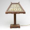 Arts  crafts lamp its fourpaneled shade with metal design laid over caramel slag glass break to wood on edge of shade 20
