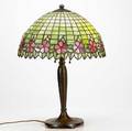 Handel table lamp with a leaded glass shade banded with pink apple bossoms over a textured copper base couple of minor breaks to glass cap repatinated base marked handel 23 x 16
