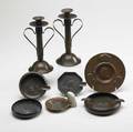Roycroft etc eight pieces pair of hammered copper candlesticks jarvie style card tray and five copper or hammered copper ashtrays one with the orb  cross mark candlesticks 9 12