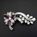 Fine diamond and ruby brooch 18k wg designed as a stylized flowerhead and ribbons brilliant marquise pear and baguette cut diamonds approx 60 cts tw and three faceted rubies approx 18 cts