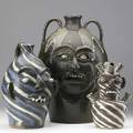 Charles lisk three folk art face jugs one of marbleized clay with several openings and blue eyes 10 one of swirled brown white and blue clay 13 and a large one with blue eyes and dripping glaze