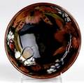 Moorcroft bowl in the orchid pattern against a red and cobalt ground stamped signature pottery to hm the queen