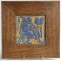 Grueby tile embossed with medieval monk playing the cello in matte blue and ochre glaze mounted in new arts  crafts frame unsigned 6 sq