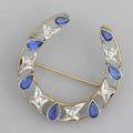 Diamond and sapphire horseshoeshaped brooch diamonds 24 ct tw and lab grown sapphires in 14k yg backing with 14k wg mounts ca 1910 10 gs gw 1 38 x 1 12