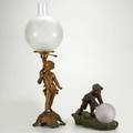 Lamps two pieces ca 1900 gilt metal putto lamp with frosted and engraved globe together with boy rolling crackled glass ball taller 25