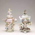 Two german porcelain urns both with floral relief decoration one depicting winged cherubs and the other with children 19th20th c taller 12 14