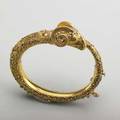 Etruscan revival 18k gold bracelet ca 1875 rams head and bypass of hinged form profusely decorated with applied wirework and granulation in neoclassical motifs indistinct marks on tongue probabl