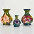 Moorcroft three cabinet vases two hibiscus and one anemone on dark green ground two marked largest 5