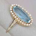 14k white gold aquamarine and seed pearl ring elongated oval faceted aquamarine 42 cts by formula in millegrained bezel setting surrounded by a halo of post set seed pearls engraved gallery and