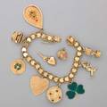Yellow gold charm bracelet and two loose charms 14k and 10k gold charms on 14k gold heart link bracelet articulated examples include green enamel shamrock typewriter birthday cake etc ca 1960