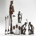 African wood carvings seven pieces including standing warrior with spear and shield on metal stand three masks on metal stand etc tallest 33 12