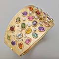 Gem encrusted 14k gold hinged cuff brightly colored oval faceted gemstones in gold bezels among prong set diamonds on florentine ground includes tourmalines garnets amethyst aquamarine peridot