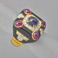 Jewel inlaid onyx and 18k gold ring cushionform onyx tablet inlaid with a central sapphire cabochon ruby cabochon corners rows of diamonds beadset in platinum and gold borders diamonds approx 