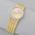 Piaget ladies 18k gold diamond watch circular gold face with arrow hands diamond bezel flexible textured strap quartz movement stem on back of case ca 1980 6 12 x 1 tapers 469 dwt gw