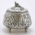 George iii silver repousse chinoiserie tea caddy round form on four mask and paw feet rococo chasing bracket scenes of chinese nobility at leisure recumbent chinese figural finial armorial crest
