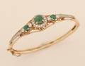 A Ladys 14 Karat Yellow Gold Diamond and Emerald Hinged Bangle Bracelet