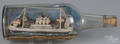 Folk art painted model ship and village in a bottle