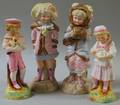 Pair of Continental Painted Bisque Girls in Winter Dress Figures and a Pair of Bisque Figures Depicting a Child Holding a Cat and a Dog